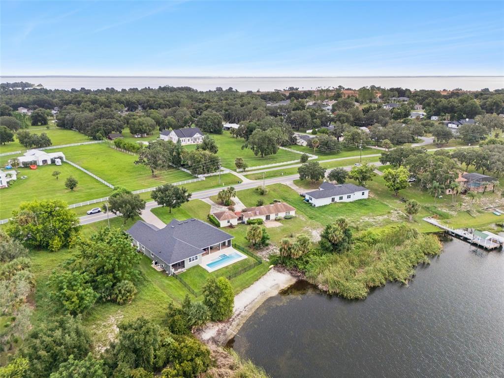 An aerial view shows several houses, a swimming pool, and a lake in a rural area — 17561 COUNTY ROAD 455, MONTVERDE, FL