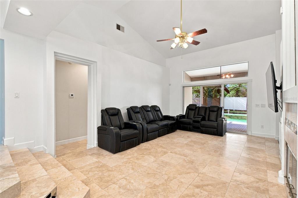 A living room features vaulted ceilings, tile flooring, black leather seating, and sliding glass doors — 13711 DORNOCH DRIVE, ORLANDO, FL