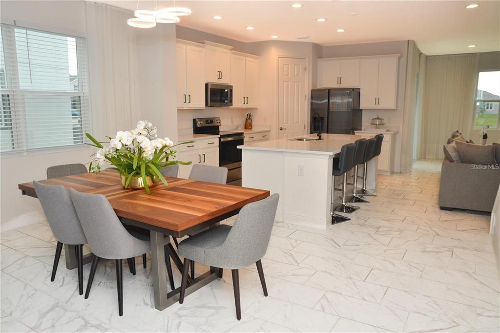 A kitchen and dining area with white cabinets, a central island, and wood-topped table — 5052 CENTER COURT, ST CLOUD, FL