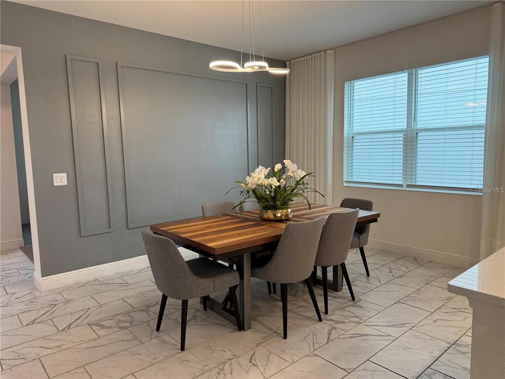 A dining room features a wooden table, gray upholstered chairs, and a paneled accent wall — 5052 CENTER COURT, ST CLOUD, FL