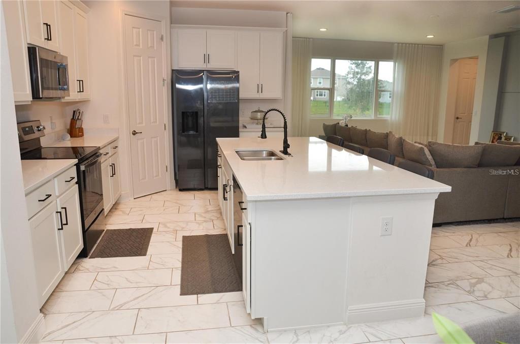 A kitchen with white cabinets, a quartz island, and marble-look tile flooring — 5052 CENTER COURT, ST CLOUD, FL