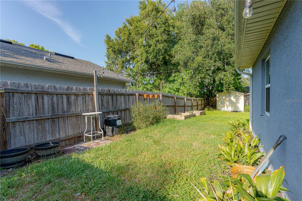 A fenced backyard features a small patio, raised garden beds, and a storage shed — 2403 MAYER STREET, ORLANDO, FL