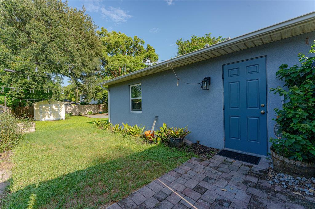 A blue exterior wall with a door, a small window, and a brick patio area — 2403 MAYER STREET, ORLANDO, FL