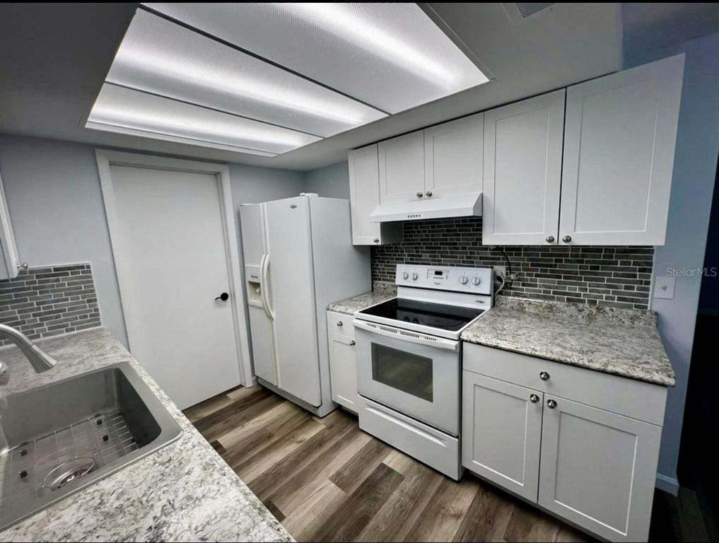 A kitchen with white cabinets, granite countertops, a tiled backsplash, and stainless steel appliances — 3331 MONTICELLO STREET, HOLIDAY, FL