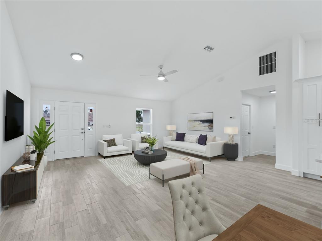 A bright living room features white walls, light wood-look tile flooring, and modern furniture — 4612 SW 149TH STREET, OCALA, FL