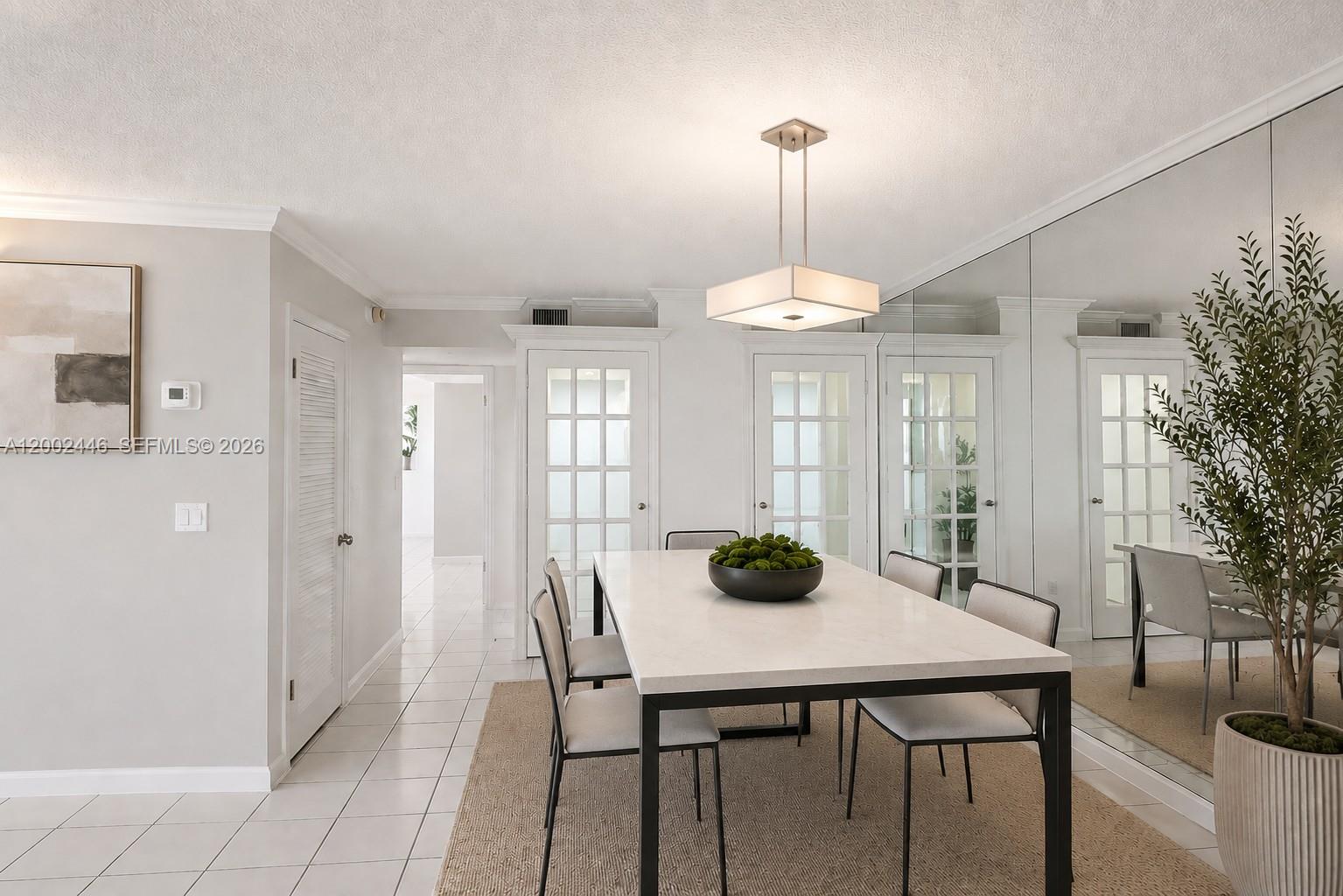 A dining room features a white table, modern chairs, a pendant light, and mirrored walls — 77 Crandon Blvd # 3C, Key Biscayne FL 33149, KEY BISCAYNE, FL