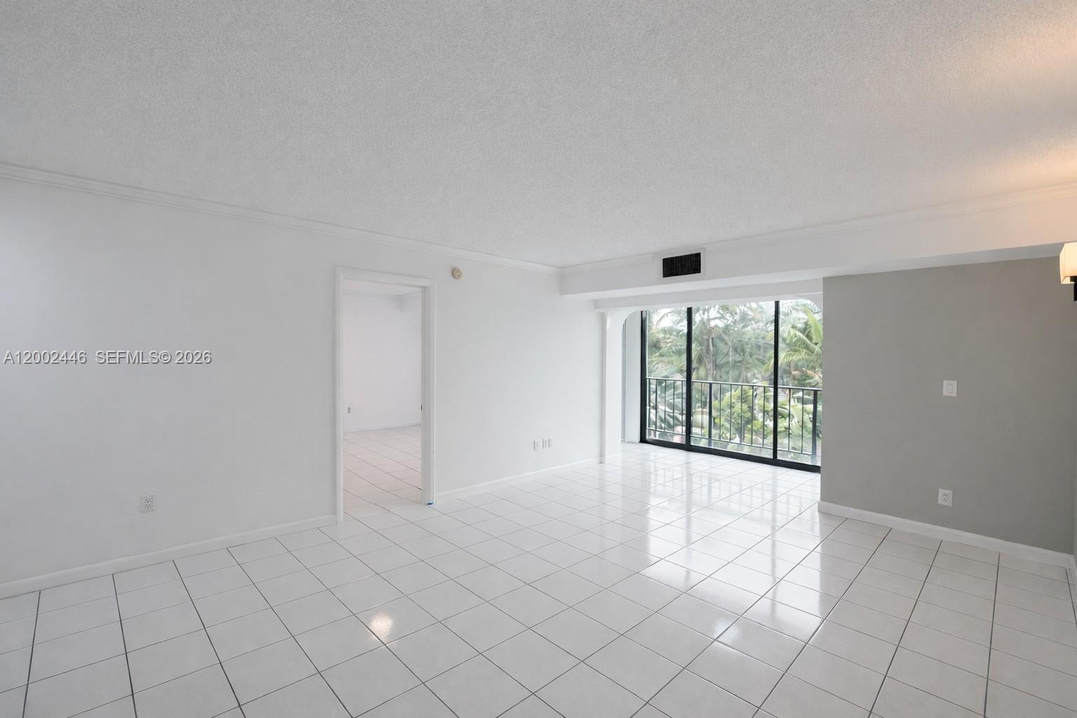 A bright living room features white tile flooring, a gray accent wall, and a balcony view — 77 Crandon Blvd # 3C, Key Biscayne FL 33149, KEY BISCAYNE, FL