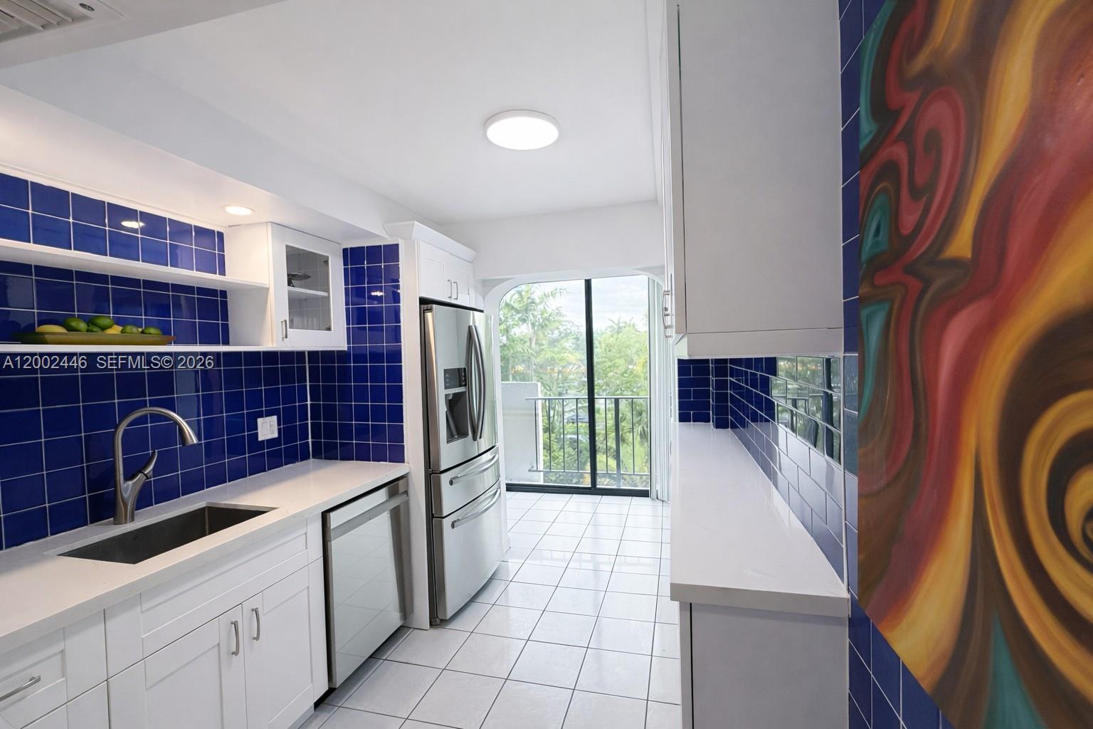 A kitchen features white cabinets, blue tiled walls, stainless steel appliances, and a balcony view — 77 Crandon Blvd # 3C, Key Biscayne FL 33149, KEY BISCAYNE, FL