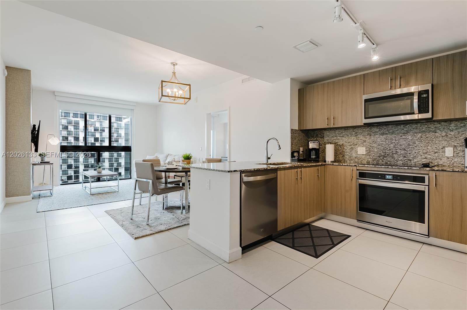 An open-concept kitchen and dining area features light wood cabinets, stainless steel appliances, and tile flooring — 5350 NW 84th Ave # 1506, Doral FL 33166, DORAL, FL