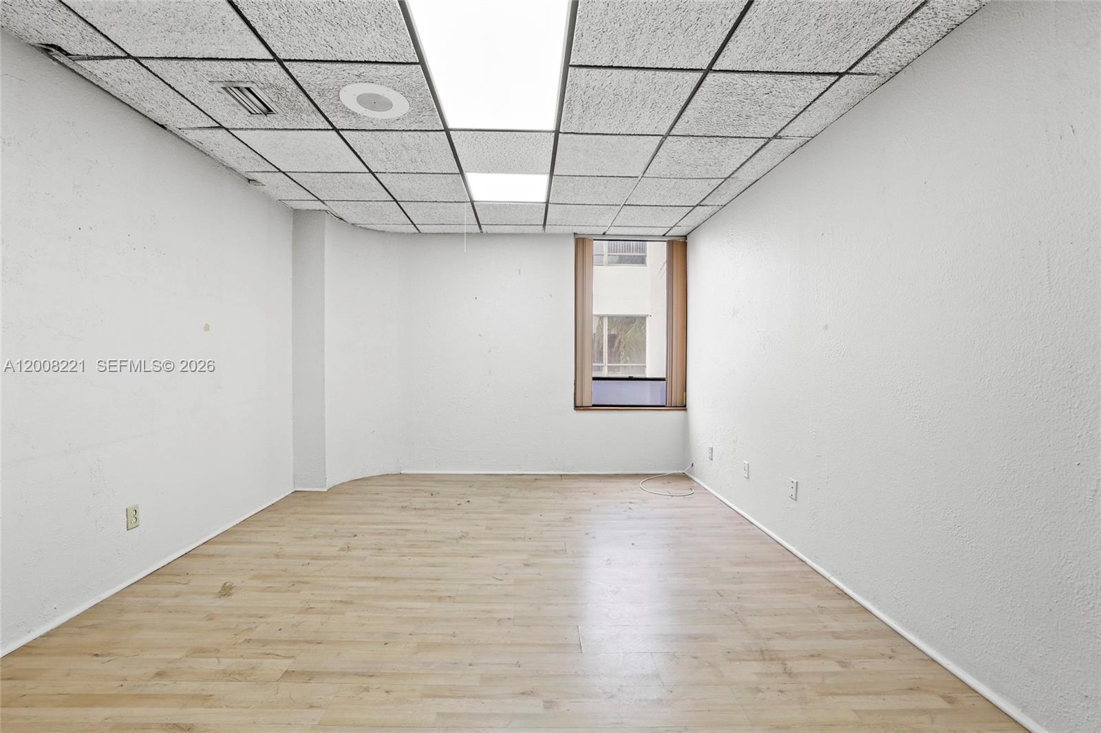 An empty office room features white walls, a drop ceiling, and light wood-look flooring — 8358 W Oakland Park Blvd # A, Sunrise FL 33351, SUNRISE, FL