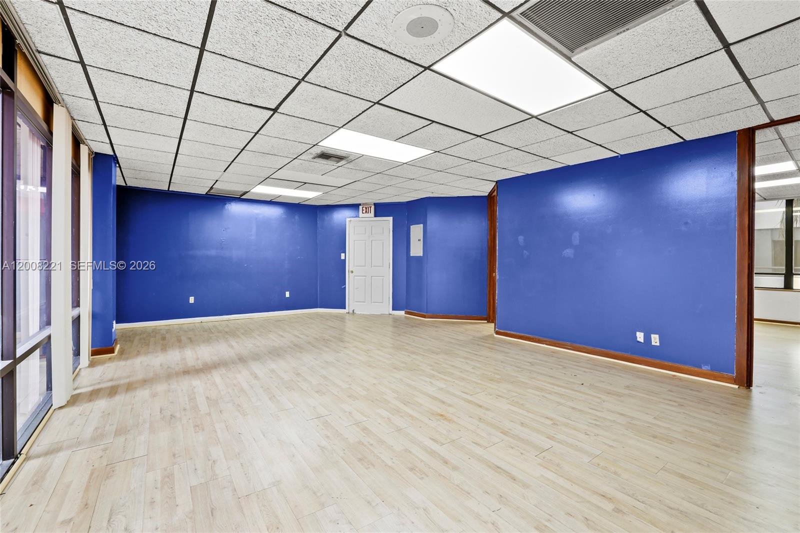 An empty room features blue walls, wood-look flooring, and a drop ceiling with recessed lighting — 8358 W Oakland Park Blvd # A, Sunrise FL 33351, SUNRISE, FL