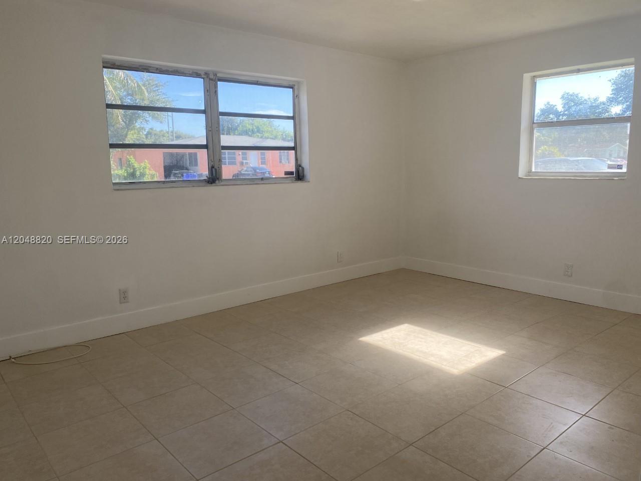 An empty room features white walls, light-colored tile flooring, and two windows — 5904 SW 27th St, West Park FL 33023, WEST PARK, FL