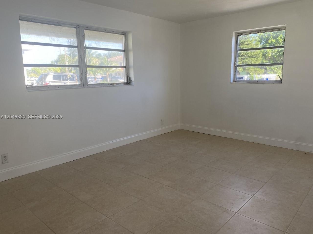 An empty room features white walls, beige tile flooring, and two windows — 5904 SW 27th St, West Park FL 33023, WEST PARK, FL
