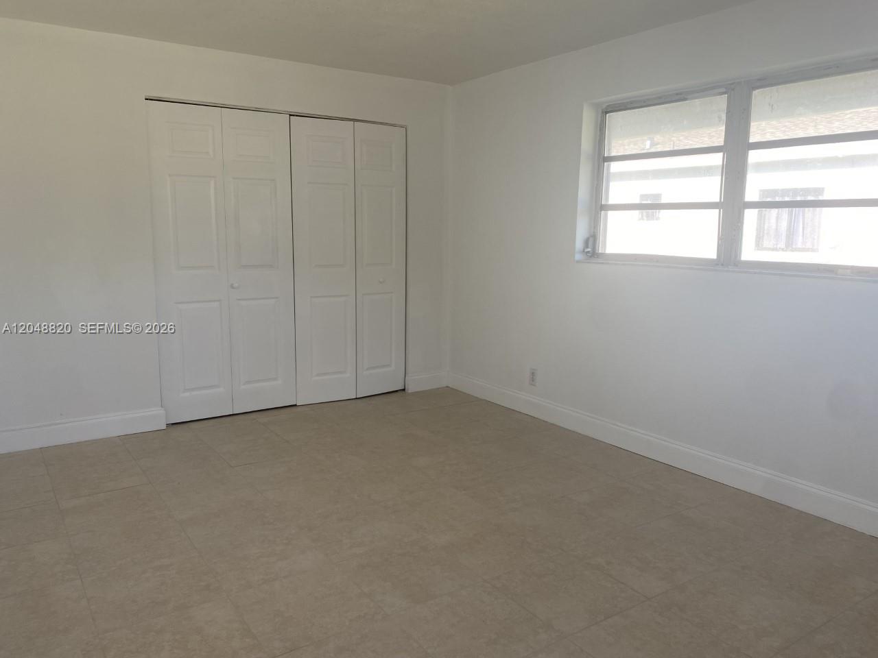 A bedroom features white walls, light-colored tile flooring, a closet with folding doors, and windows — 5904 SW 27th St, West Park FL 33023, WEST PARK, FL