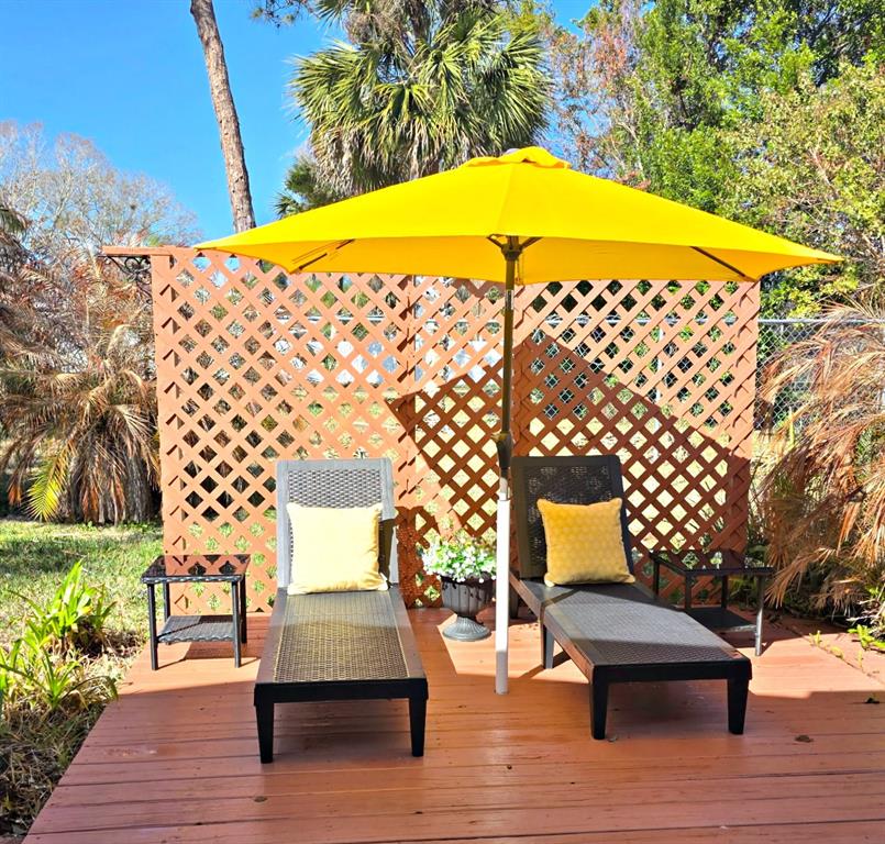 A wooden deck features two lounge chairs, side tables, and a yellow umbrella — 727 ROLLING HILLS DRIVE, PORT ORANGE, FL