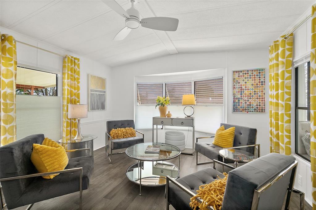 A bright living room features grey armchairs, yellow accent pillows, and a glass coffee table — 727 ROLLING HILLS DRIVE, PORT ORANGE, FL