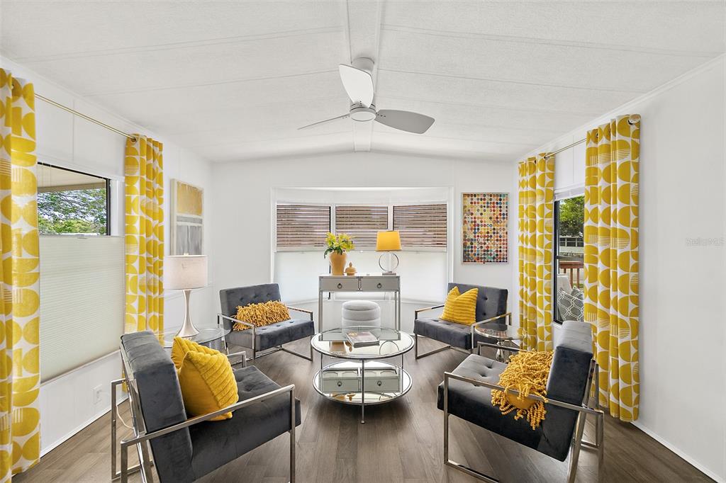 A living room features four dark gray chairs, a round glass table, and yellow patterned curtains — 727 ROLLING HILLS DRIVE, PORT ORANGE, FL