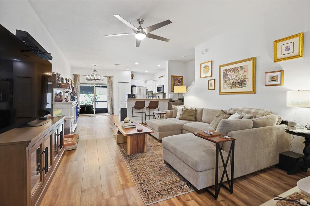 A living room with a sectional sofa, wood flooring, and an open kitchen in the background — 2709 ISABELLA VALLEY COURT, BRANDON, FL