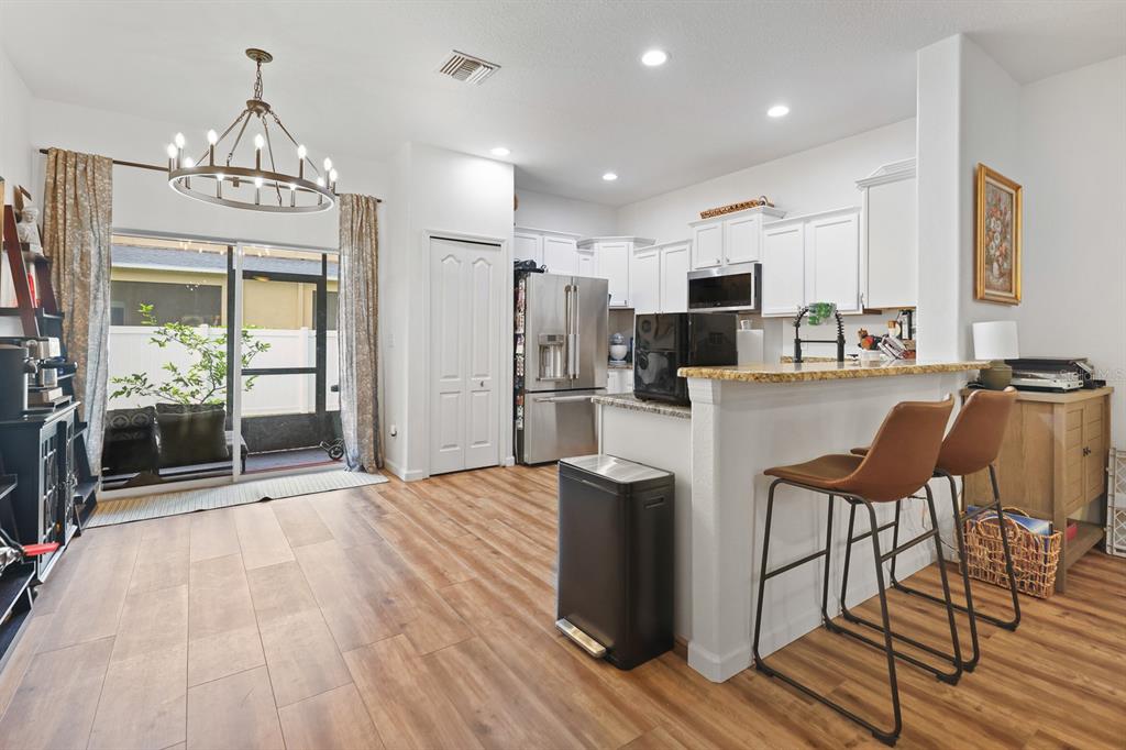 A kitchen with white cabinets, granite countertops, and a breakfast bar with two leather stools — 2709 ISABELLA VALLEY COURT, BRANDON, FL