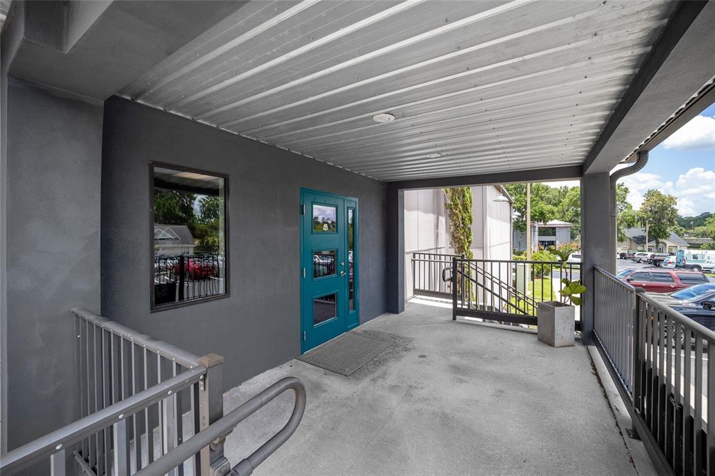 A covered concrete balcony features a teal door, a window, and metal railings — 2300 SE 17TH STREET UNIT 1100, OCALA, FL