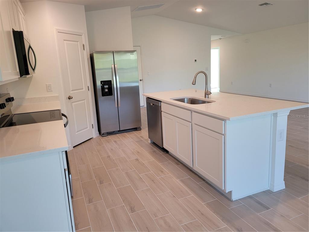 A modern kitchen features white cabinets, stainless steel appliances, a center island, and tile flooring — 6305 SHAW STREET, ENGLEWOOD, FL