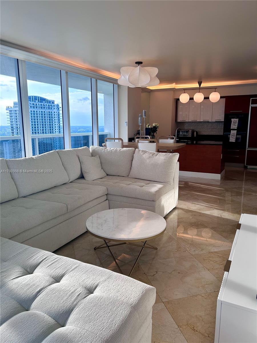 A modern living room features a large sectional sofa, marble coffee table, and floor-to-ceiling windows — 1830 S Ocean Dr # 4106, Hallandale Beach FL 33009, HALLANDALE BEACH, FL