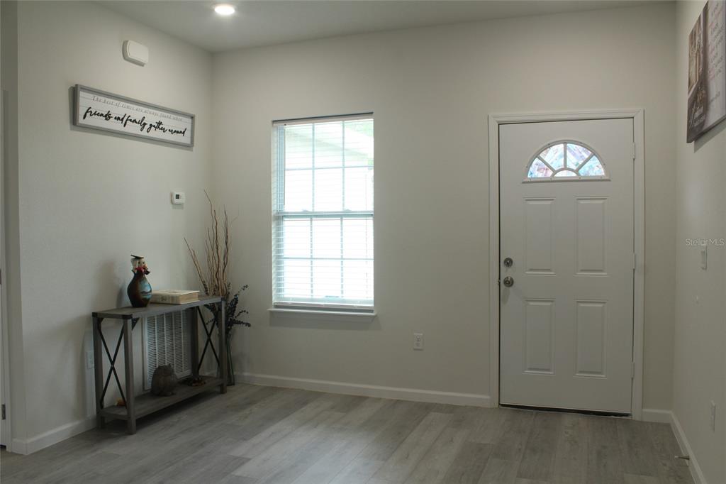 An entryway features light wood-look flooring, a white front door, and a console table — 1787 SW 168TH LOOP, OCALA, FL