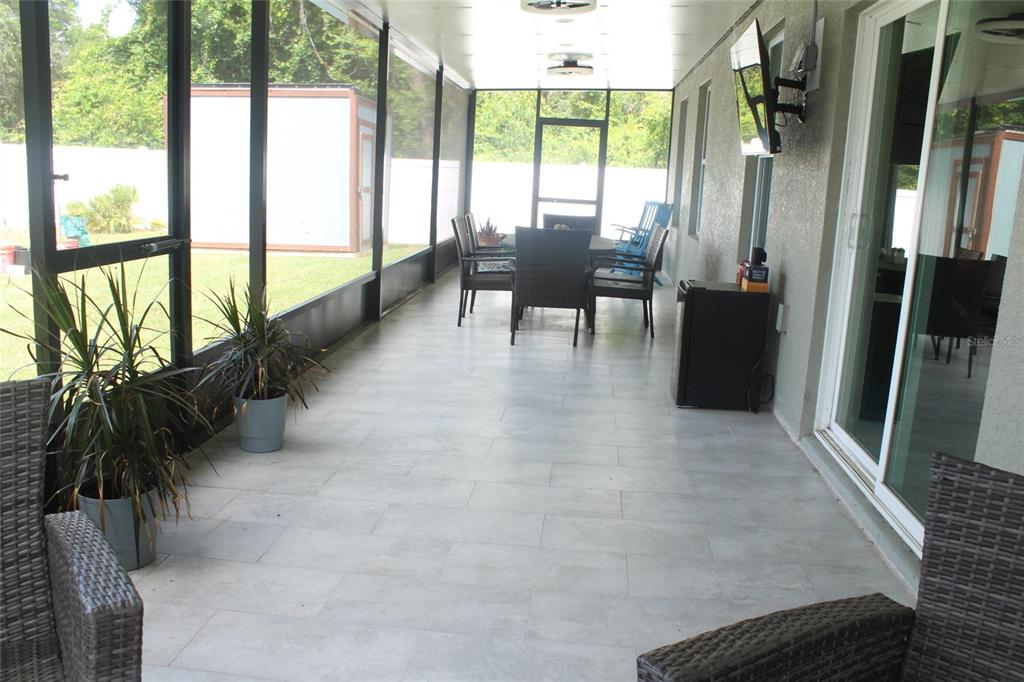 A screened-in patio features tiled flooring, outdoor furniture, and a view of the backyard — 1787 SW 168TH LOOP, OCALA, FL