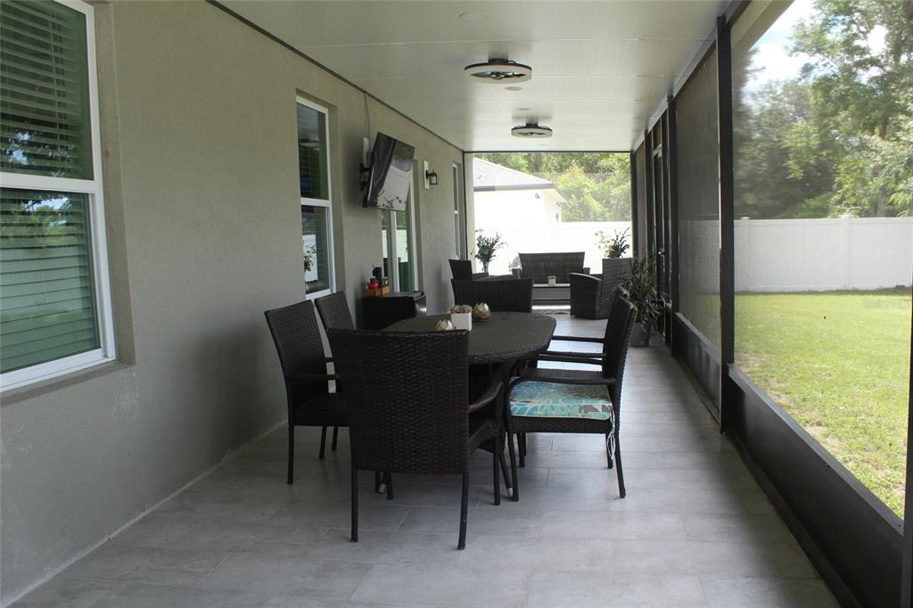 A covered patio features tiled flooring, wicker dining furniture, and a screened-in view of a yard — 1787 SW 168TH LOOP, OCALA, FL