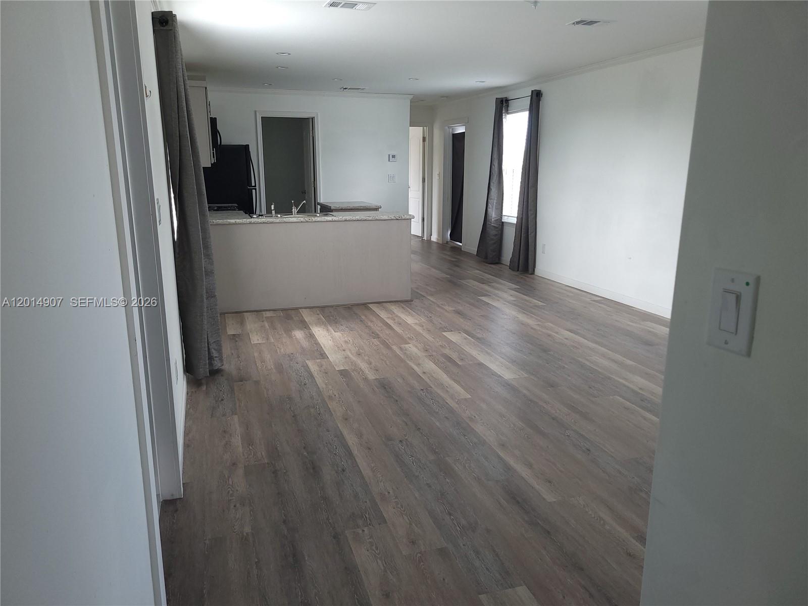 An open-concept living area features wood-look flooring, white walls, and a kitchen island — 799 Hazel St # 799, Key Largo FL 33037, KEY LARGO, FL