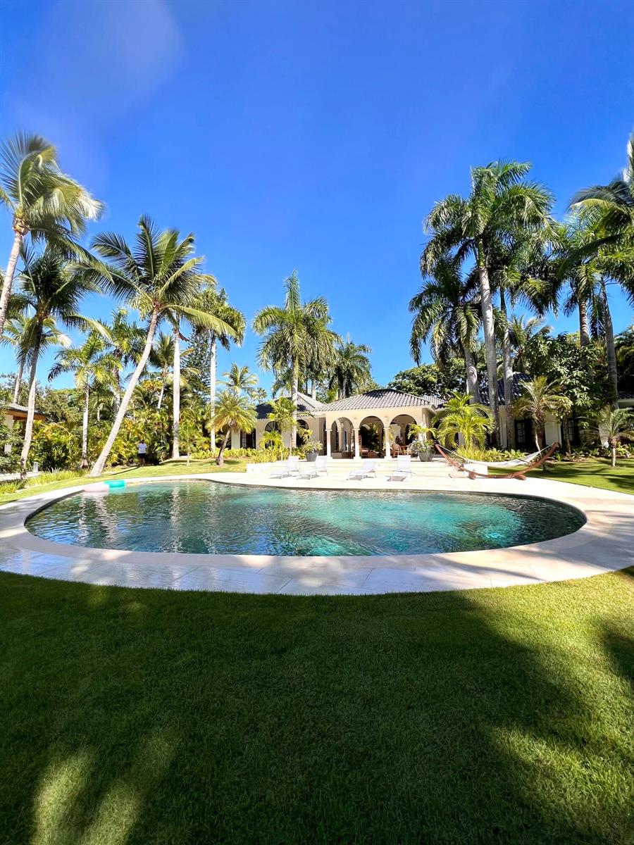 A swimming pool sits in front of a house surrounded by many tall palm trees — 123456 Sea Horse Ranch Community, FL