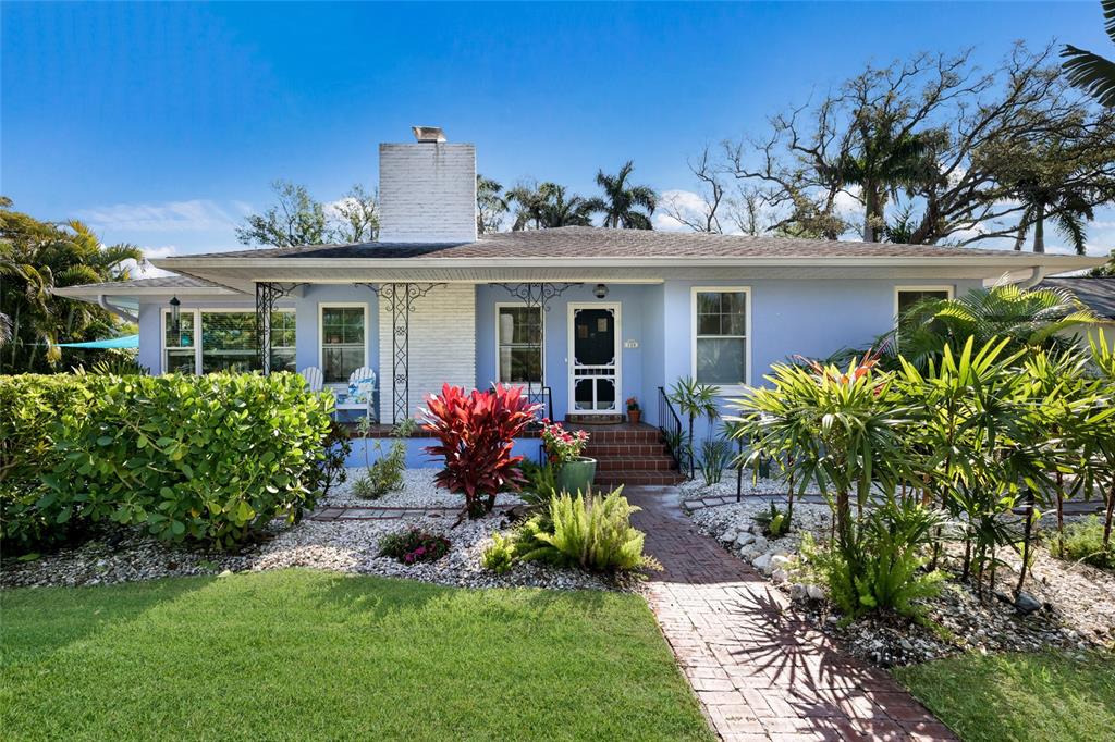 A light blue single-story house with a white brick chimney and a brick walkway — 104 24TH STREET NW, BRADENTON, FL