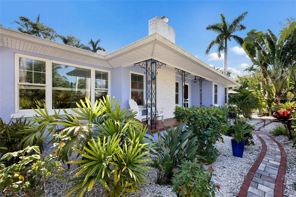 A light blue house with a white brick chimney and a covered front porch — 104 24TH STREET NW, BRADENTON, FL