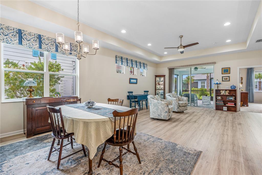A dining area with a wooden table and chairs flows into a living space with sliding doors — 466 MARGARITAVILLE AVENUE, DAYTONA BEACH, FL