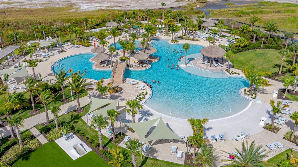 An aerial view of a large resort-style swimming pool with palm trees and lounge chairs — 466 MARGARITAVILLE AVENUE, DAYTONA BEACH, FL