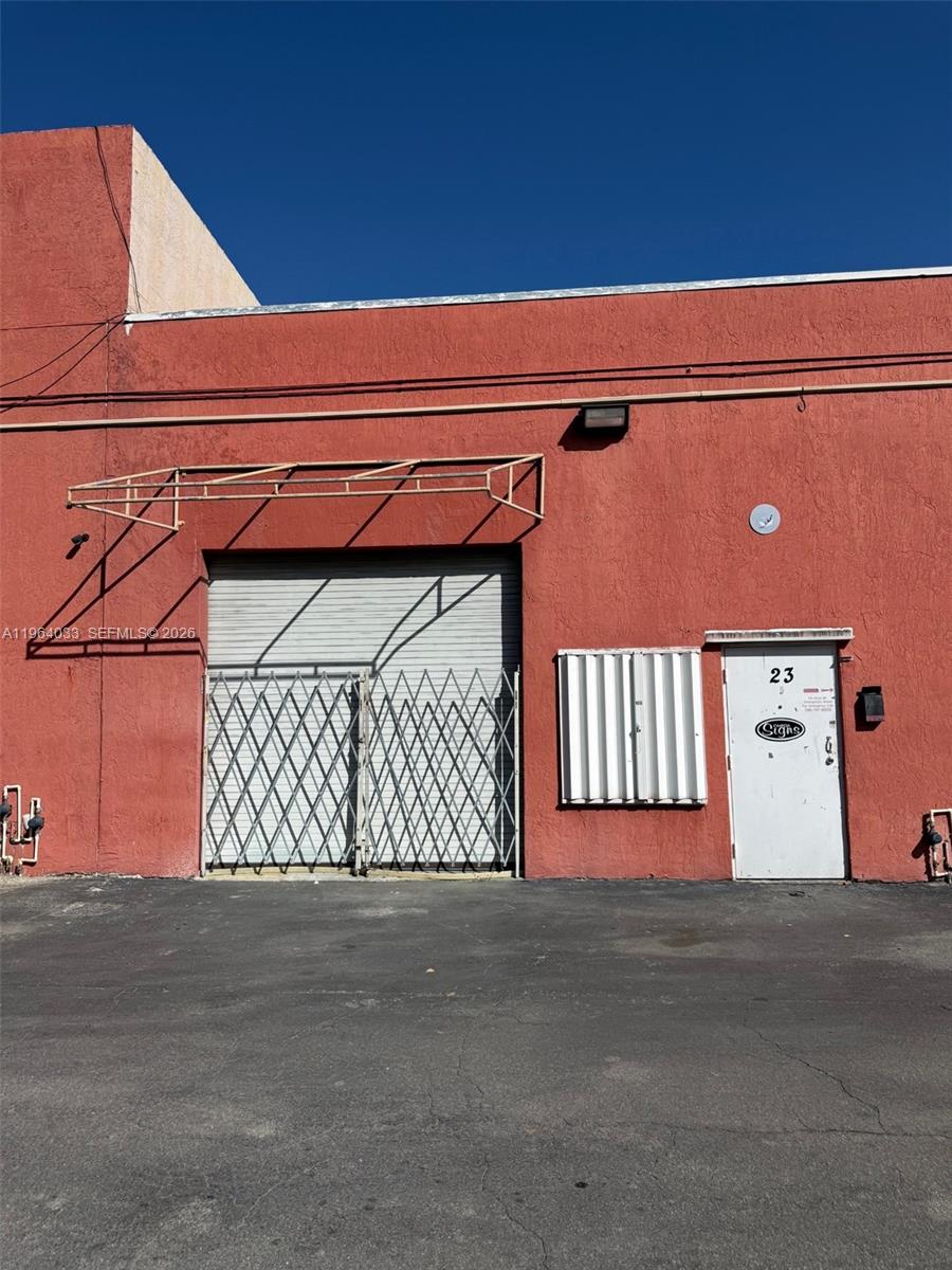 The exterior of a red industrial building features a roll-up door, a pedestrian door, and awnings — 13690 SW 142nd Ave # A, Miami FL 33186, MIAMI, FL