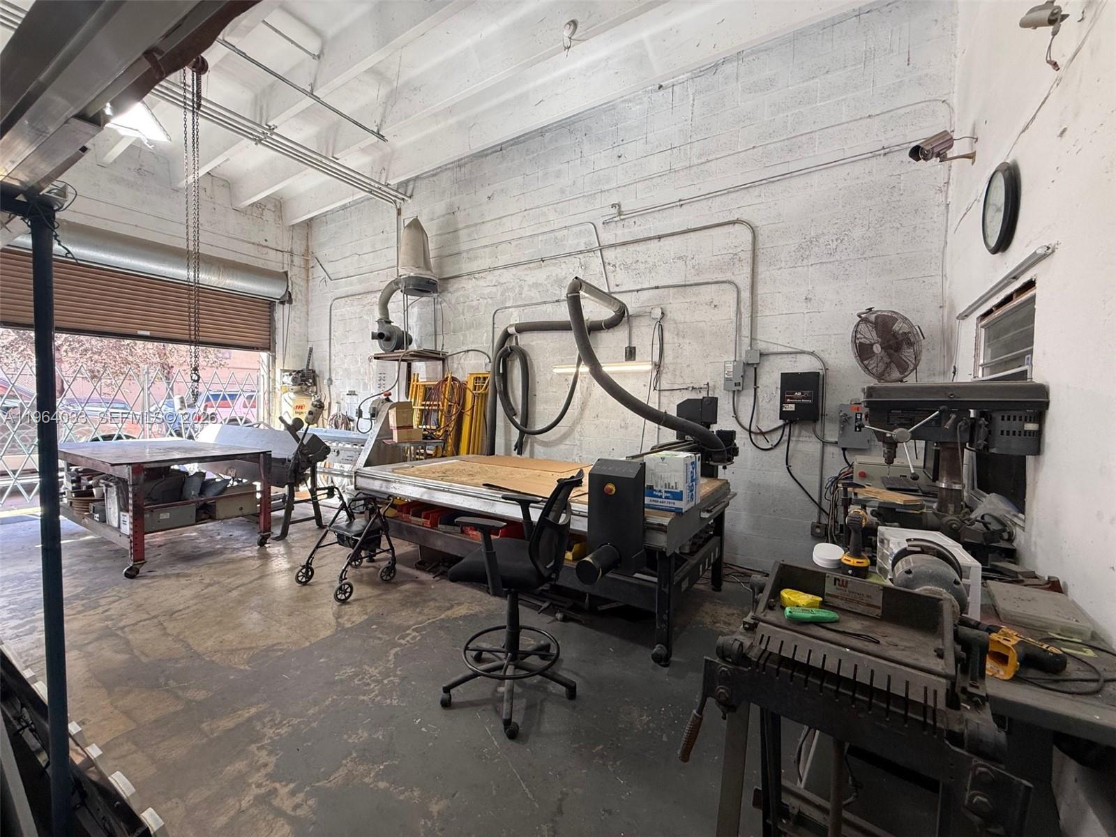 A workshop features concrete block walls, a CNC machine, a metal workbench, and industrial equipment — 13690 SW 142nd Ave # A, Miami FL 33186, MIAMI, FL