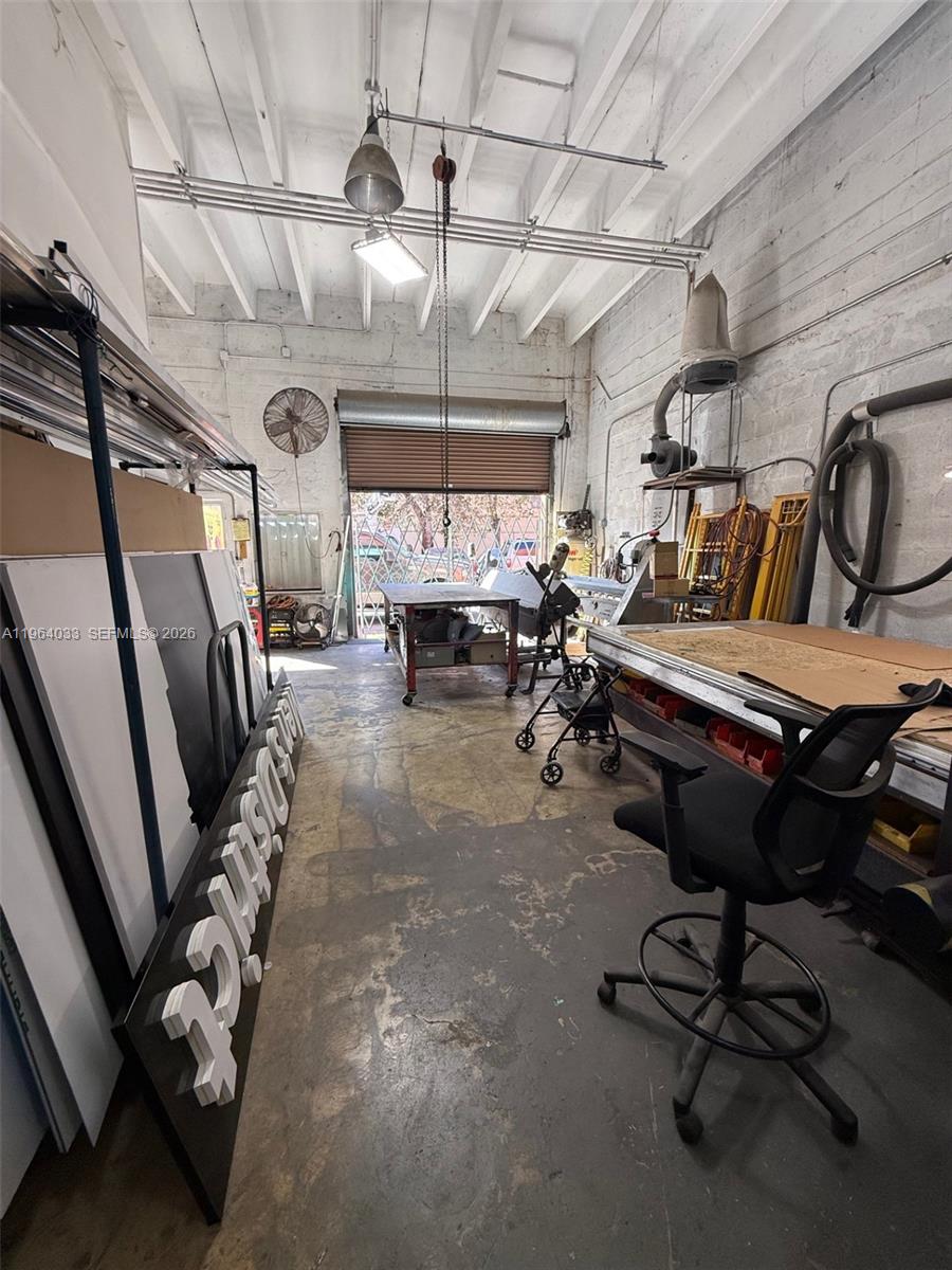 This industrial workshop features a concrete floor, exposed ceiling beams, and various workbenches and equipment — 13690 SW 142nd Ave # A, Miami FL 33186, MIAMI, FL