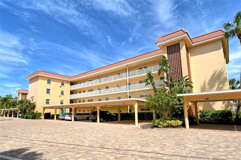 A multi-story apartment building features a covered parking area and a paved driveway — 1257 S PORTOFINO DRIVE UNIT 307, SARASOTA, FL