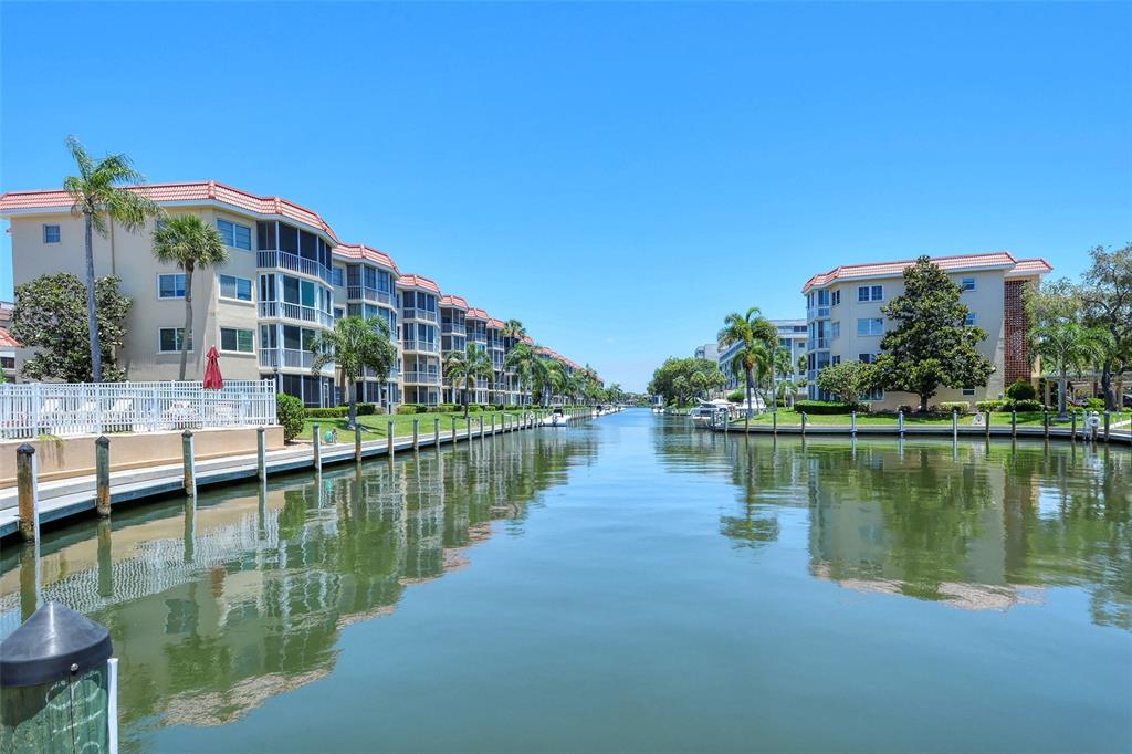 A canal flows between two multi-story apartment buildings with boat docks and palm trees — 1257 S PORTOFINO DRIVE UNIT 307, SARASOTA, FL