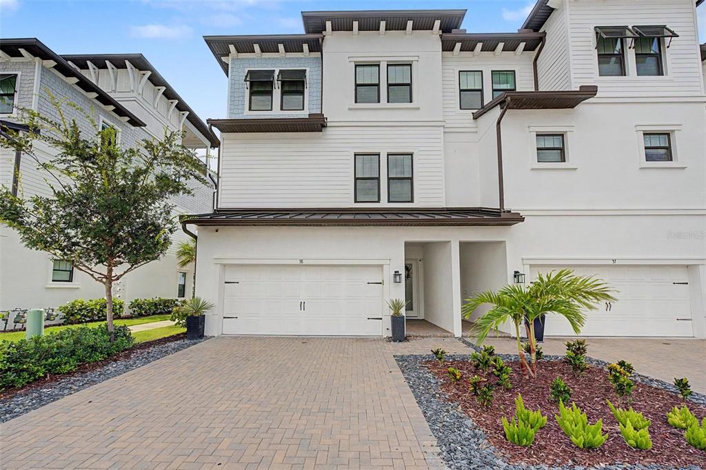 A three-story white townhouse with a two-car garage and a paved driveway — 5351 BRIDGE STREET UNIT 38, TAMPA, FL