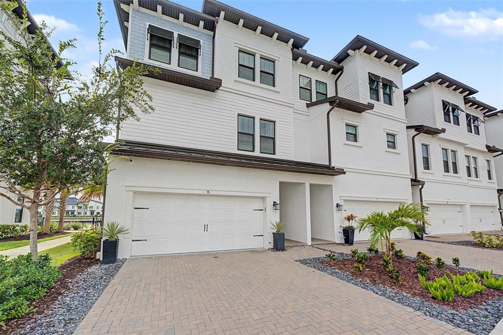 A three-story townhouse with a white facade, a two-car garage, and a paved driveway — 5351 BRIDGE STREET UNIT 38, TAMPA, FL