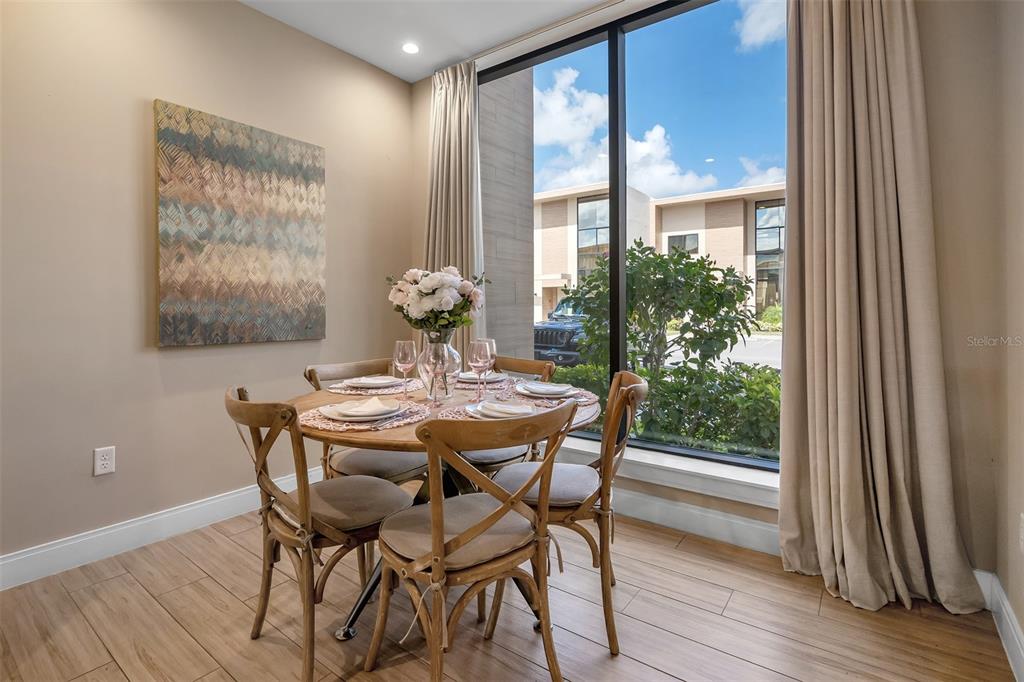 A dining area features a round wooden table with four chairs and a large window — 7567 BROOKLYN DRIVE, KISSIMMEE, FL
