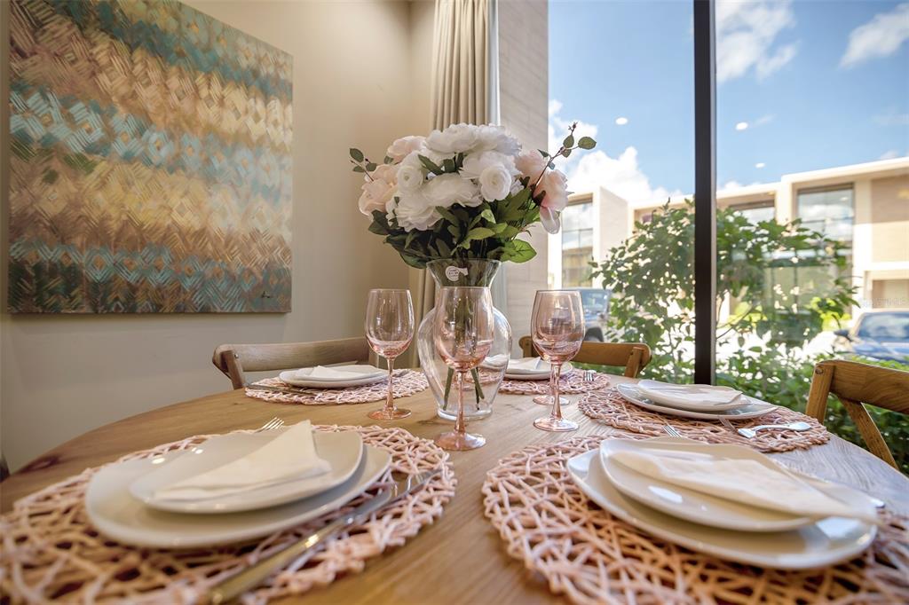 A dining table is set with plates, napkins, and a floral centerpiece near a window — 7567 BROOKLYN DRIVE, KISSIMMEE, FL
