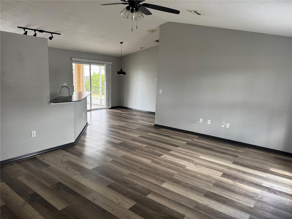 An open-concept living area features gray walls, wood-look flooring, a kitchen peninsula, and sliding doors — 6289 MARINER BOULEVARD, SPRING HILL, FL