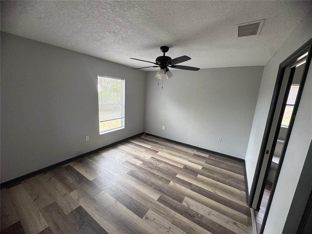 An empty bedroom features light gray walls, dark wood-look flooring, and a ceiling fan — 6289 MARINER BOULEVARD, SPRING HILL, FL