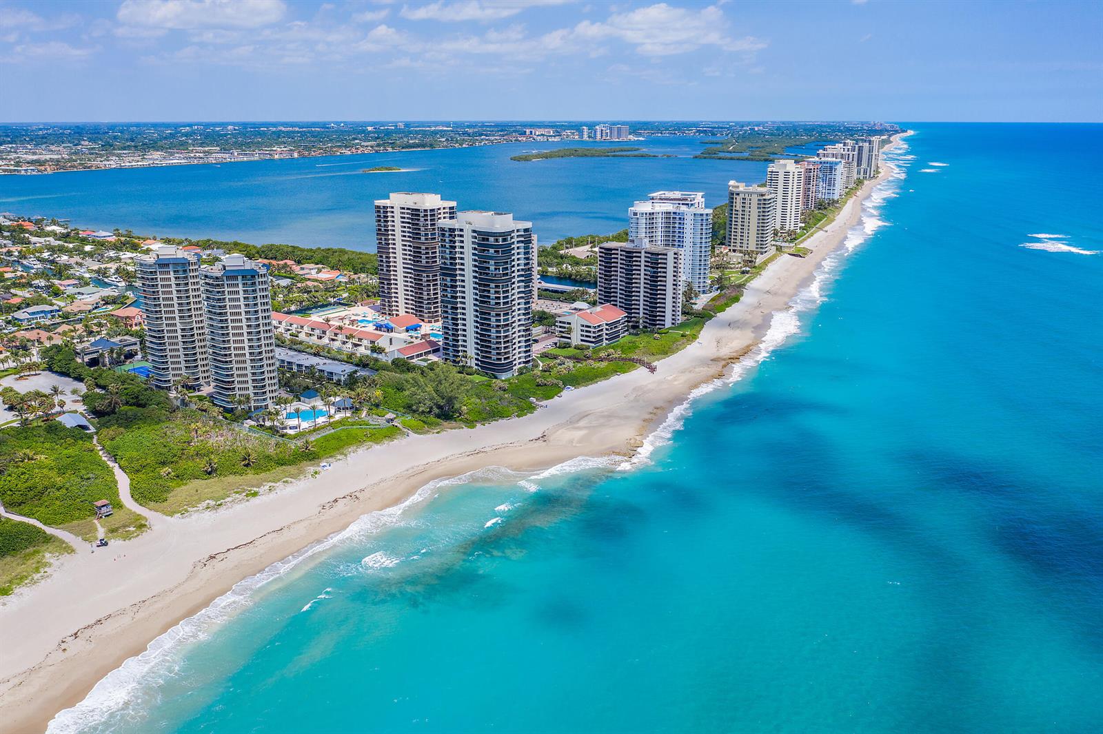An aerial view of high-rise residential buildings situated along a sandy beach and turquoise ocean — 4000 N Ocean Drive # 2004, Singer Island FL 33404, SINGER ISLAND, FL