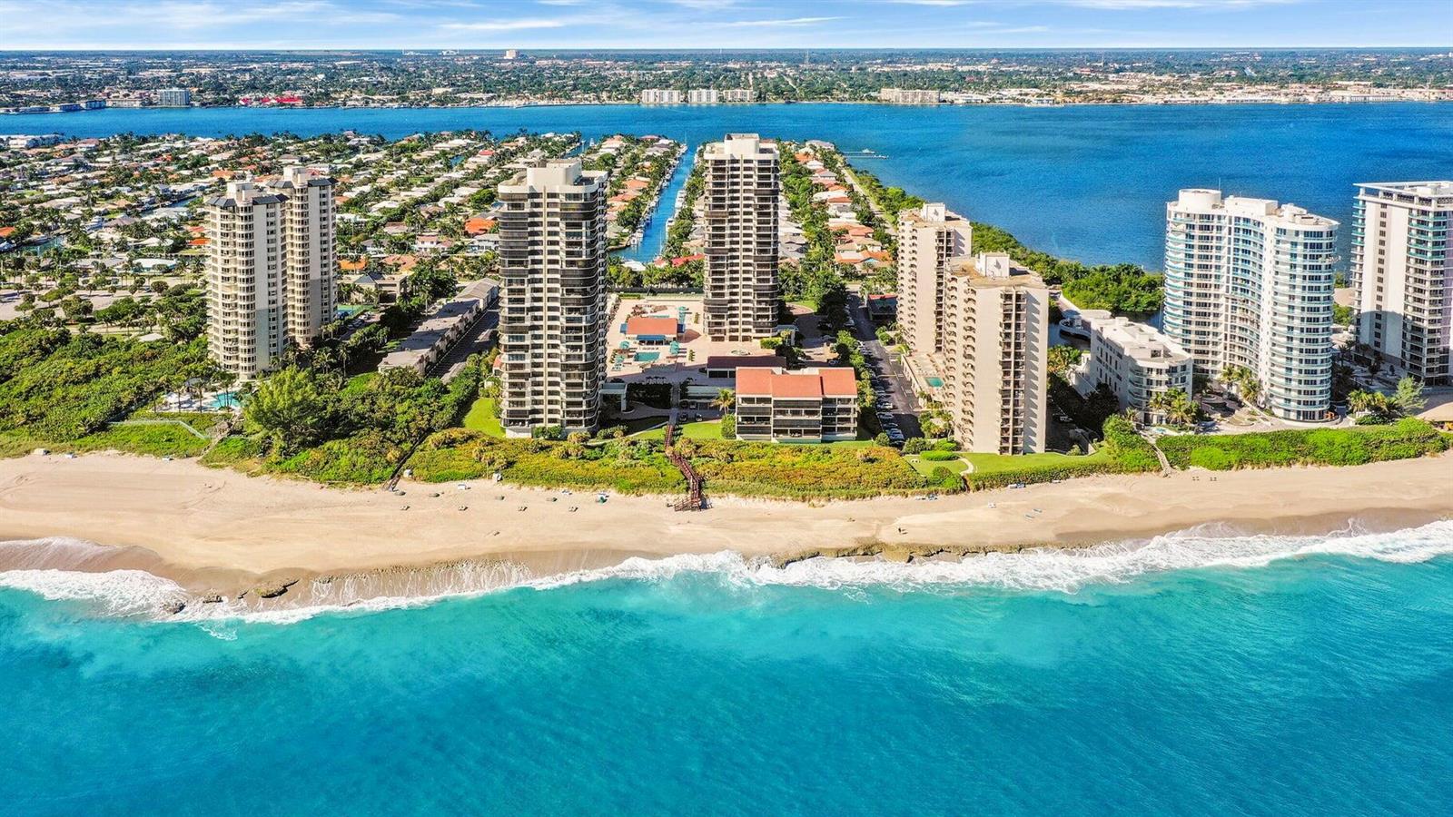 An aerial view of high-rise residential buildings situated along a sandy beach and turquoise ocean — 4000 N Ocean Drive # 2004, Singer Island FL 33404, SINGER ISLAND, FL