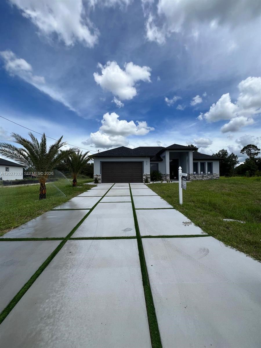 A modern single-story house with a concrete driveway and two palm trees in the yard — 616 Maple Ave N, Lehigh Acres FL 33972, LEHIGH ACRES, FL