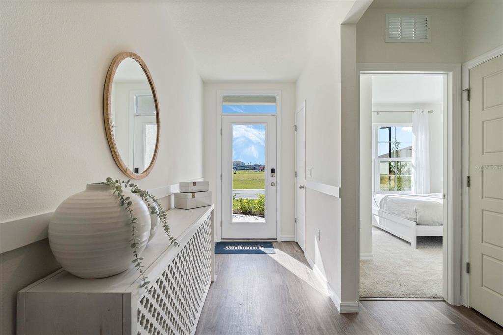 A bright entryway features a white console table, oval mirror, and a view of the outdoors — 2759 ADELINE AVENUE, WINTER HAVEN, FL
